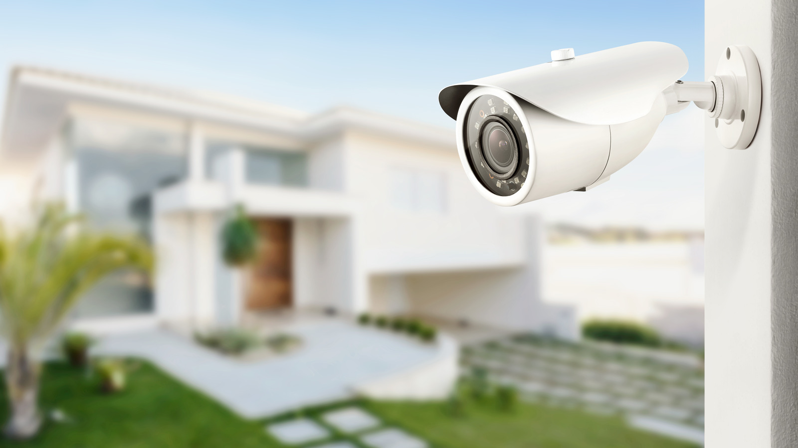 Three quarter view of varifocal surveillance camera, with a house on background